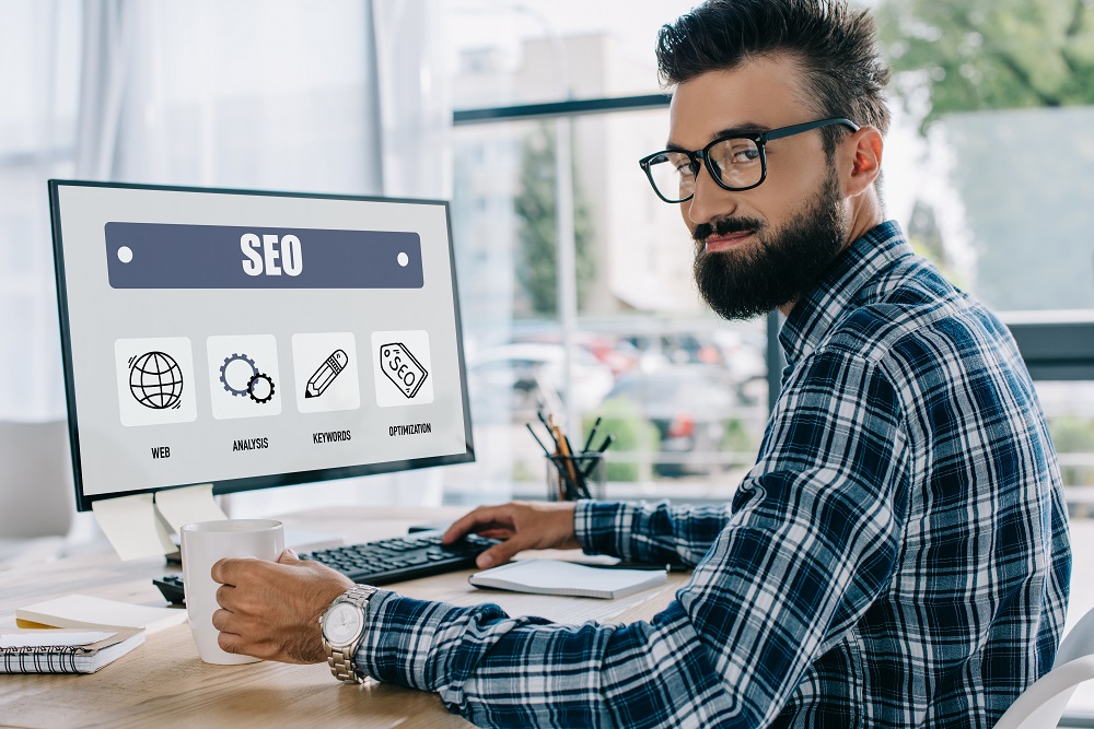 young successful seo manager sitting at workplace with computer and looking at camera Advantages of the Organic SEO